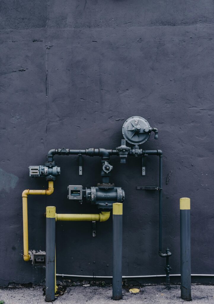Pipes and machinery against an urban building wall with a gritty industrial look.